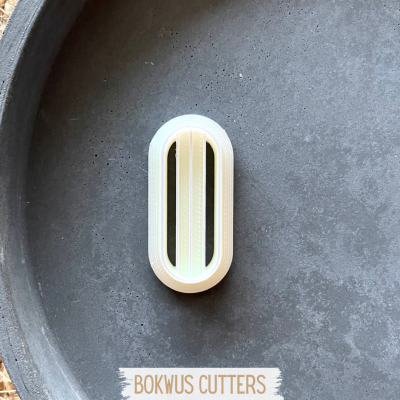 Cortador oval branco com lâminas douradas sobre superfície preta