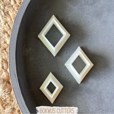 Três cortadores losango brancos sobre prato cinza com tapete bege ao lado
