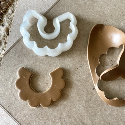 Cortador de massa branco e pedaço de massa castanha em azulejo bege