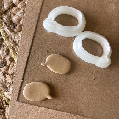 Molduras plásticas brancas e peças de argila marrom em forma de boca sobre cartão castanho