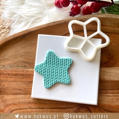 Cortador de biscoitos estrela branco e biscoito azul claro com textura sobre azulejo branco e tabuleiro de madeira