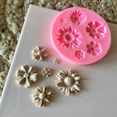 Molde silicone rosa com formas de flores e flores creme decorativas sobre superfície branca