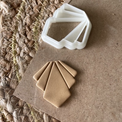 Marcadores de páginas em formas geométricas em tons castanhos e branco sobre superfície castanha e tapete tecido.