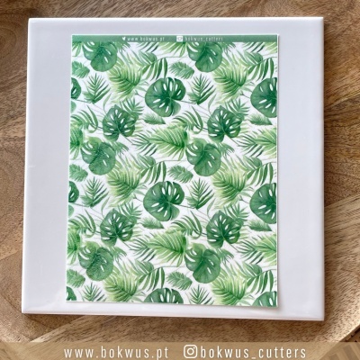 Prato branco quadrado com folha decorativa de padrão de folhas tropicais verdes sobre base de madeira clara