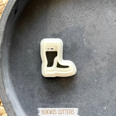 Cortador de bolachas em forma de bota de plástico branco sobre superfície preta