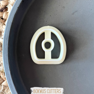 Cortador branco em forma de ferradura com círculo no meio sobre superfície cinzenta