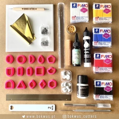 Materiais de artesanato para modelação e corte de massa polimérica organizados em superfície clara