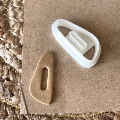 Cortador de massa branco em plástico ao lado de massa cortada bege sobre madeira e esteira