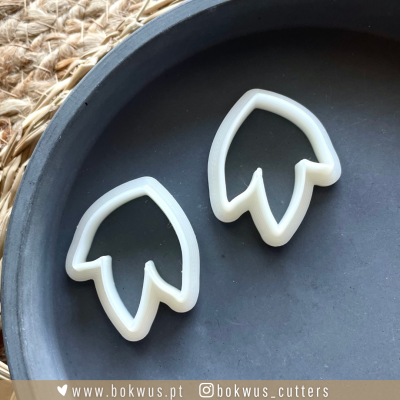 Dois cortantes para bolachas em formato de folhas em prato preto sobre tecido rústico