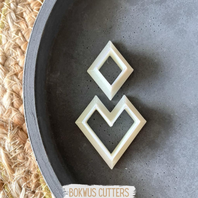 Conjunto de cortadores de biscoito em forma de losango sobre prato cinzento e fundo de fibras naturais