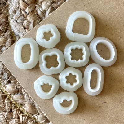 Anéis brancos plásticos com diferentes formas e texturas sobre madeira clara e tapete de fibras