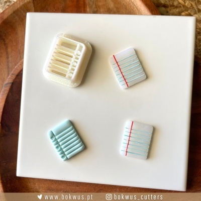 Cortadores em forma de folhas de caderno com linhas coloridas em suporte branco