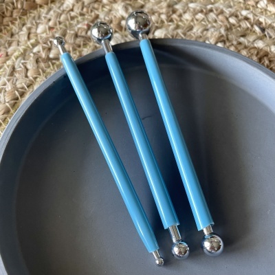 Três ferramentas azuis com bolas metálicas nas pontas em prato cinza
