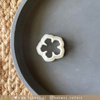 Fatiadora de legumes branca em forma de flor num prato cinzento sobre tapete de sisal