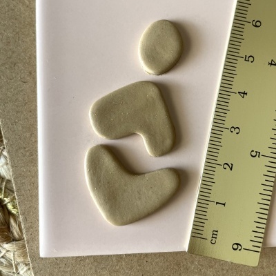 Três peças de argila cinza clara e régua amarela sobre superfície branca