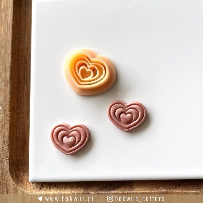 Cortadores de biscoitos em forma de coração em plástico laranja e rosa sobre placa branca