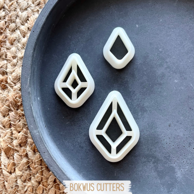 Três cortadores de plástico branco com padrão geométrico num tabuleiro cinzento.