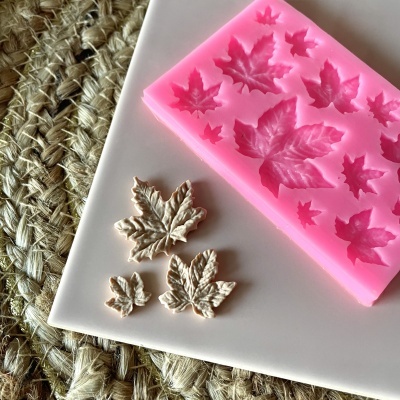 Molde de silicone rosa com folhas e folhas brancas feitas ao lado em superfície branca