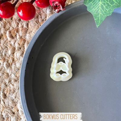 Cortante de sino de Natal branco em prato cinza com bagas vermelhas e folhas verdes