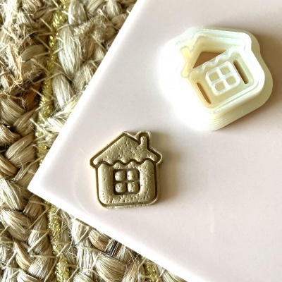 Carimbo branco em forma de casa com selo castanho em relevo sobre fundo branco e tapete de fibras naturais