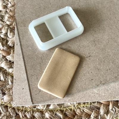 Peças retangulares branca e bege sobre cartão castanho e tapete de palha