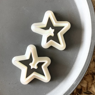 Brincos brancos em forma de estrela sobre prato cinza