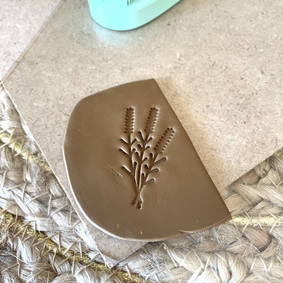 Fragmento de silicone castanho com relevo de ramo sobre tapete trançado