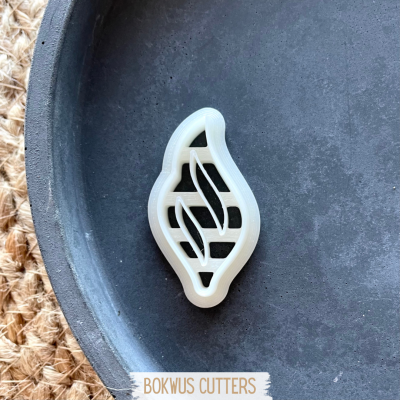 Cortante plástico branco em forma de vela num prato preto