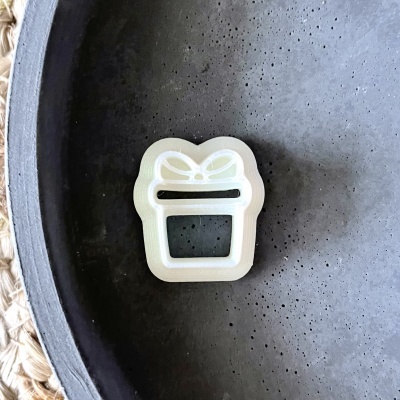 Molde branco para biscoitos em forma de caixa de presente com laço sobre superfície cinzenta