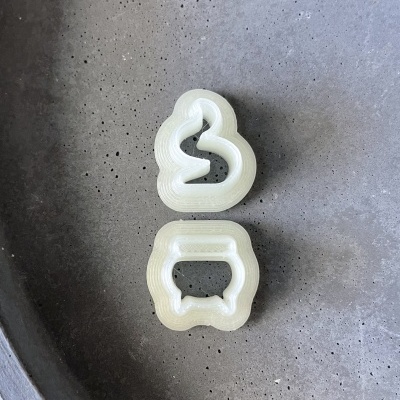 Duas cortantes de plástico translúcido em forma de pato e vaso sobre superfície cinza texturizada