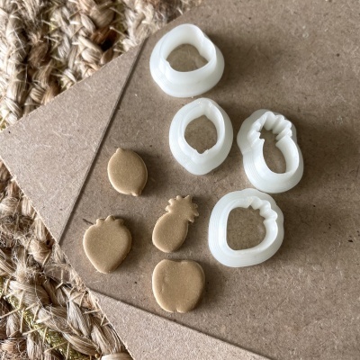 Conjunto de cortadores de fruta em plástico branco com formas de massa dourada