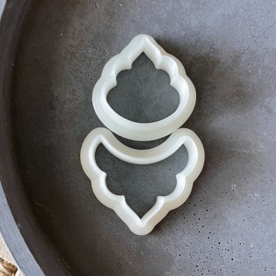 Dois cortadores de biscoito brancos em superfície cinza texturada.