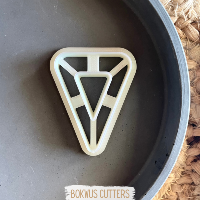 Cortador triangular branco dentro de frigideira preta sobre superfície de palha