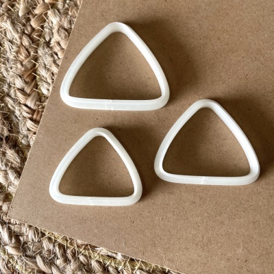 Três argolas triangulares brancas sobre superfície castanha e tapete de fibra