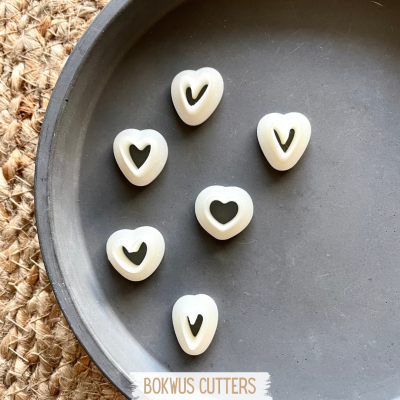 Seis cortadores de biscoito em forma de coração branco numa bandeja preta