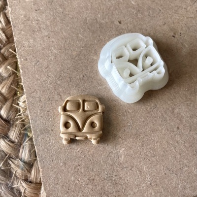 Miniatura de furgão bege e peça plástica branca sobre superfície castanha e tecido trançado