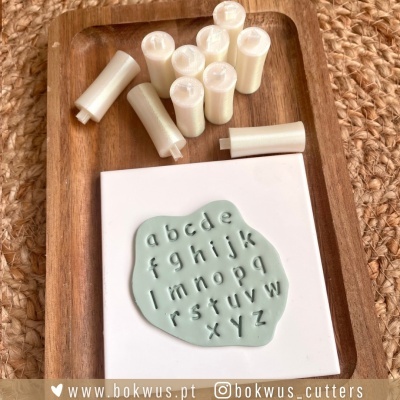 peças cilíndricas brancas e placa com letras do alfabeto em relevo