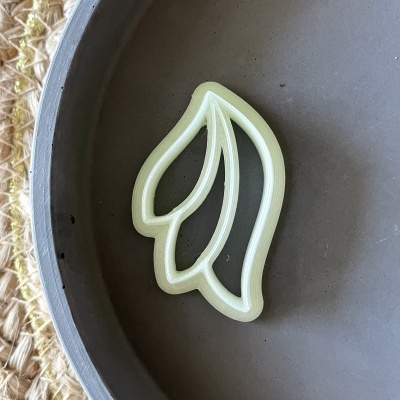 Forma de corte em plástico creme com desenho de folhas sobre prato cinzento