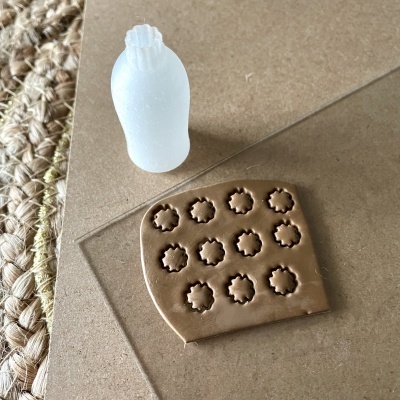 Bloco de massa castanha com carimbos de flores e ferramenta branca para carimbos