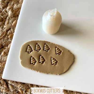 Carimbo branco de árvore de Natal e massa cortada em forma de árvores sobre placa branca