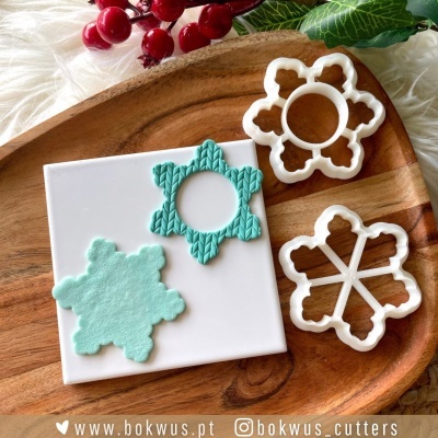 Cortadores de massa em forma de floco de neve em plástico branco sobre tábua de madeira