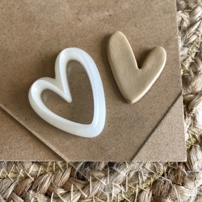 Dois corações decorativos, plástico branco e massa de modelar bege sobre cartão castanho em tecido rústico