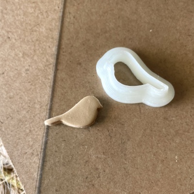 Carimbo branco em forma de pássaro com impressão castanha do pássaro sobre superfície castanha.