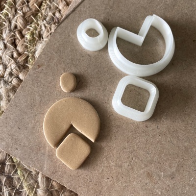 Moldes plásticos brancos e peças de argila bege sobre cartão castanho e tapete trançado