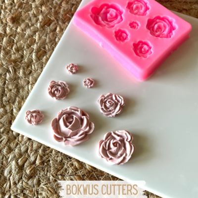 Molde de silicone rosa com formas de flores e flores moldadas rosa sobre superfície branca e tecido rústico