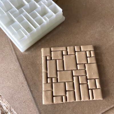 Molde de plástico branco e peça castanha com padrão de blocos retangulares