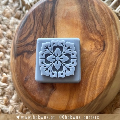 Carimbo cinzento com padrão floral em relevo sobre base de madeira natural