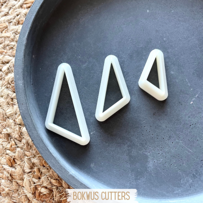 Três cortadores triangulares brancos em prato escuro sobre tecido de juta