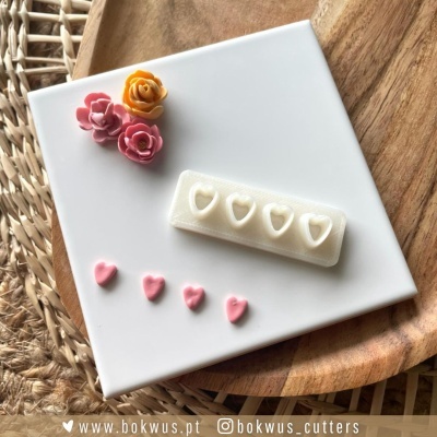 Molde e decorações em forma de corações e flores num prato branco sobre base de madeira