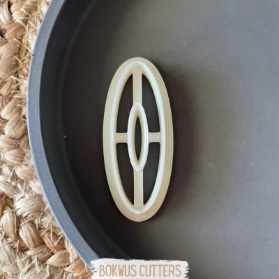 Cortador oval branco sobre prato cinzento com fundo de rattan trançado e etiqueta BOKWUS CUTTERS